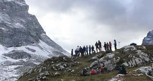Gruppe von Kollegiaten steht auf einem Bergkamm im Gebirge