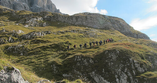 Weite Aufnahme einer grünbewachsenen Gebirgslandschaft mit Outdoor-Gruppe