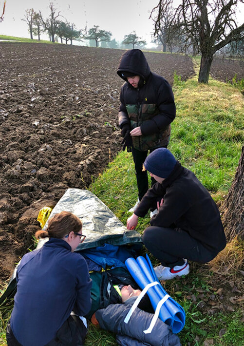 Junge Menschen auf einem Feld helfen verletzter Person