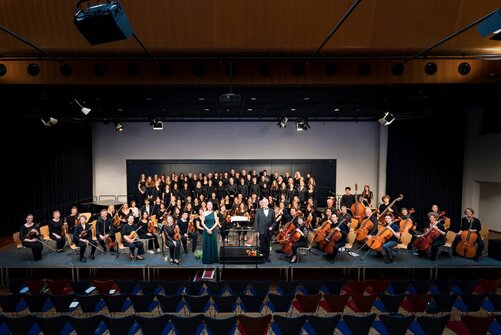 Gruppenfoto des Orchesters vor Aufführung, Chor hinter Musikern, T. Braun davor