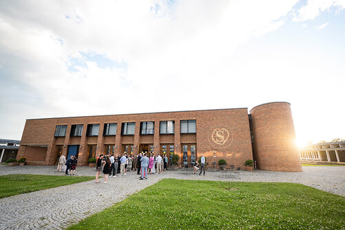 Kollegiat:innen und Gäste am Hauptgebäude des Campus Härlen bei Sonnenuntergang.