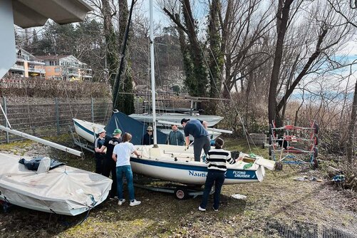 Kollegiat:innen putzen ein Segelboot, welches noch an Land steht. 