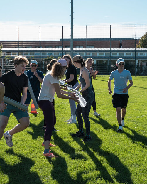 Kollegiaten auf dem Sportplatz mit Röhren in der Hand bei einem Kennenlernspiel