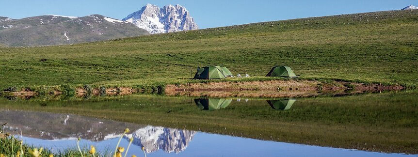 Wasseroberfläche eines Gebirgssees mit Bergen im Hintergrund.