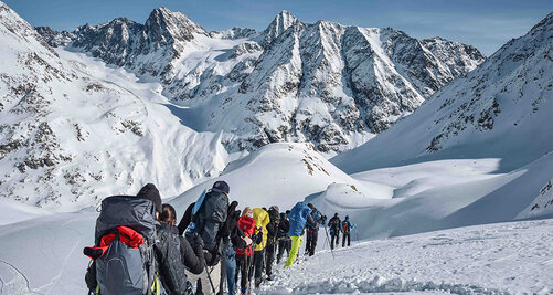 Outdoorgruppe wandert durch die mit Schnee bedeckte Berglandschaft 