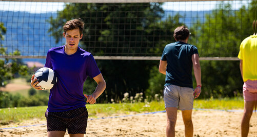 Kollegiate hält eine Vollyball in der Hand auf den Volleyballfeld am Campus Härlen des Salem Kolleg in Überlingen.