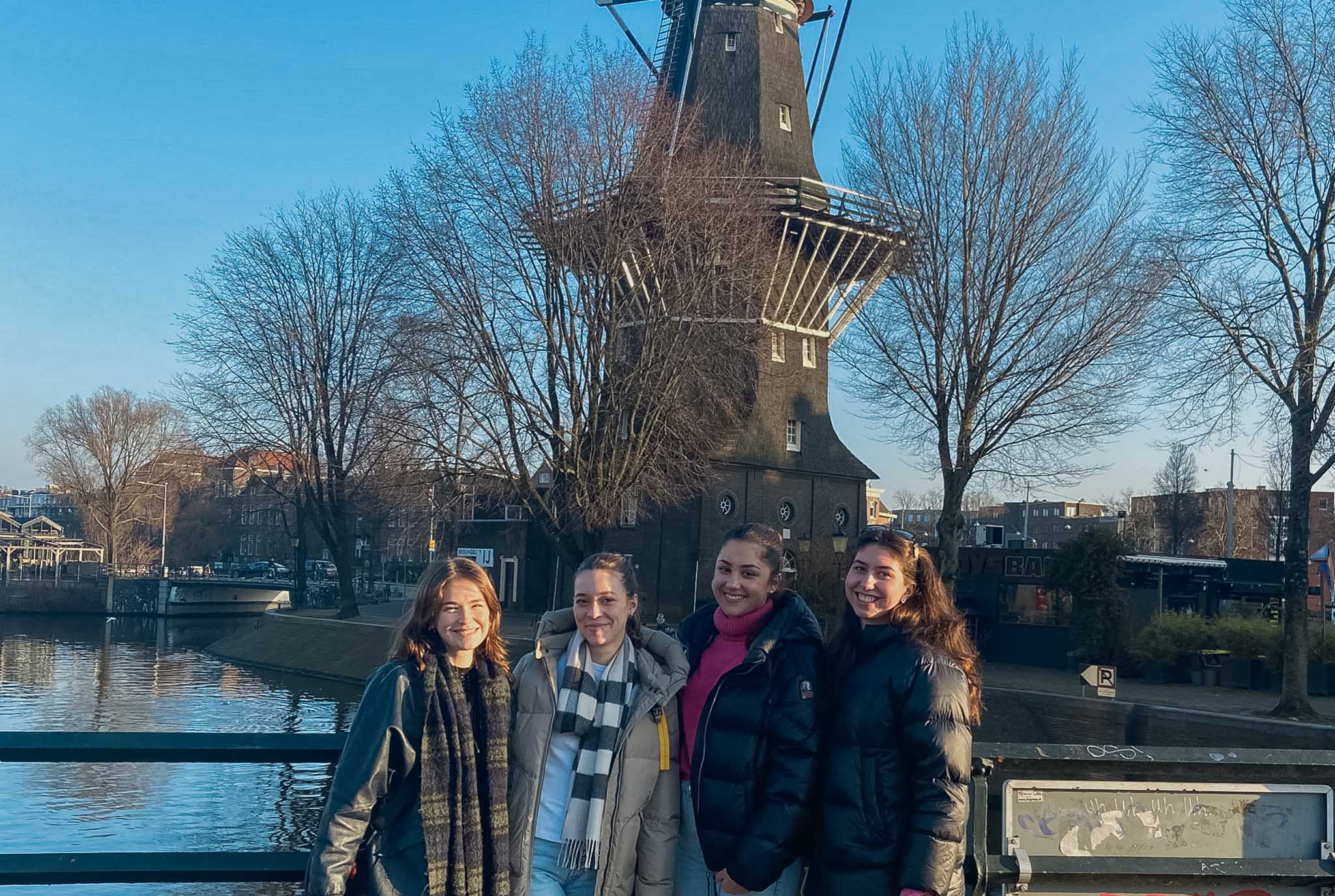 Projektgruppe steht vor einer holländischen Windmühle in Amsterdam.