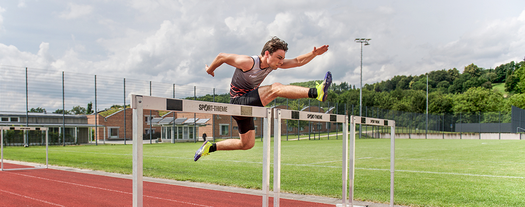 Ein Kollegiat springt auf der Kunststoffbahn des Sportplatzes Campus Härlen über eine Hürde