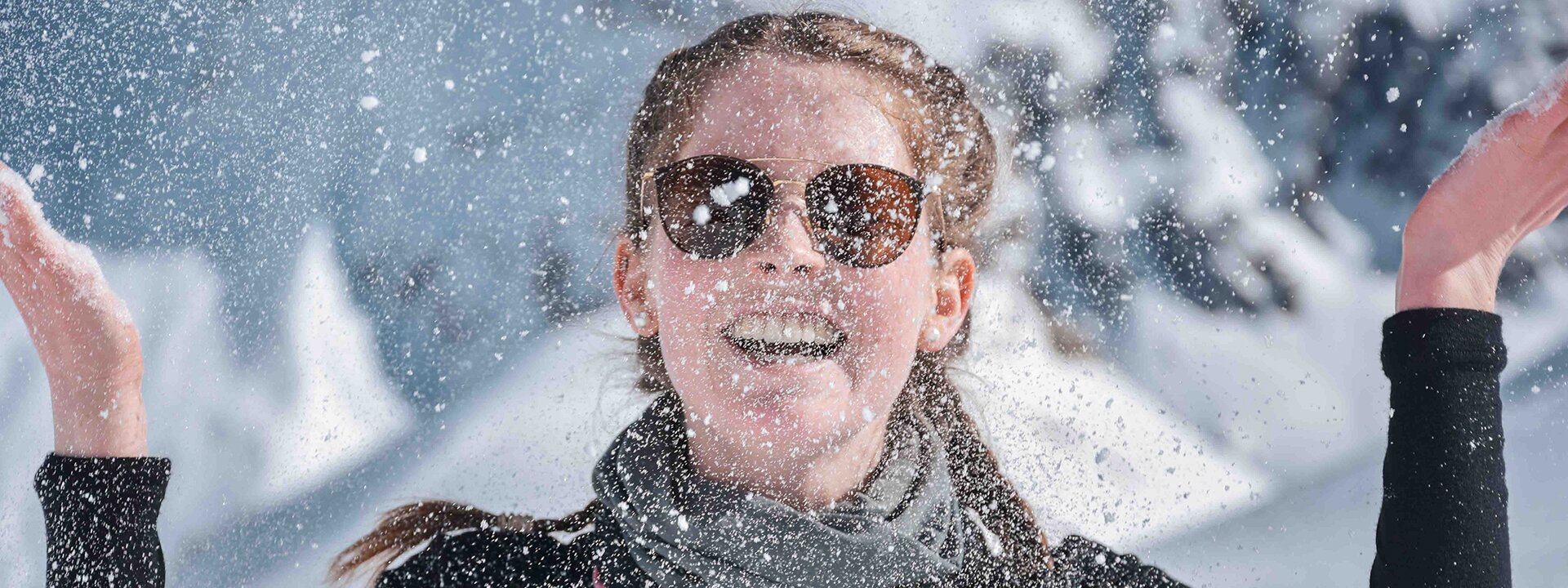 Kollegiatin wirft zerstäubten Schnee auf der Alpinexkursion. Outdoor Education im Schnee.